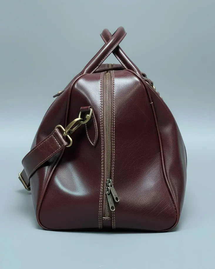 Brown leather bag with gold zippers AND SHOULDER STRAP on a textured white surface