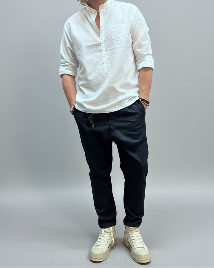 Person wearing a white shirt and blue pants with white sneakers in an industrial setting.