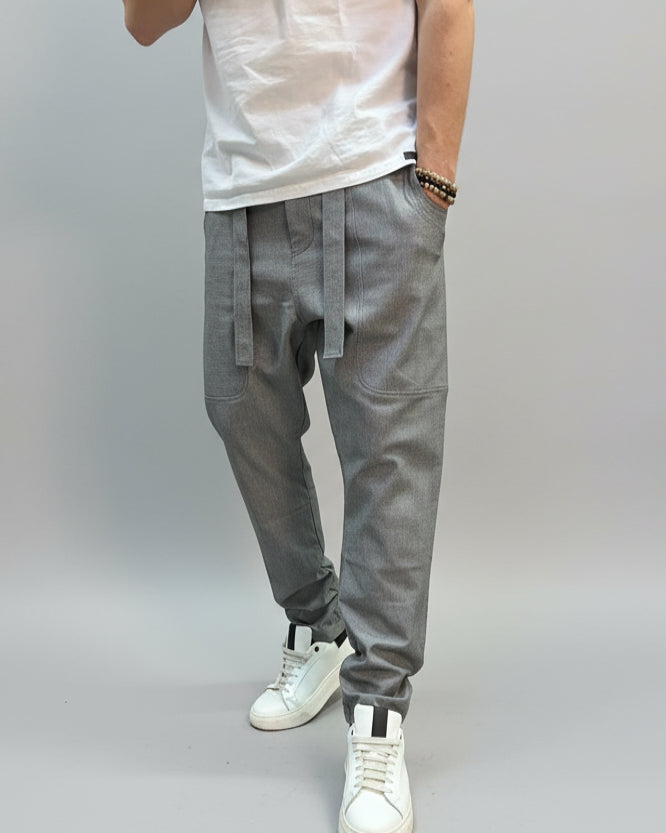 Person wearing grey dogtooth pants and white T-shirt and white sneakers on a gray floor.