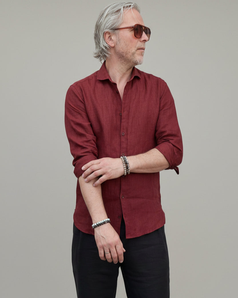 Man wearing a red shirt and sunglasses against a light grey backdrop