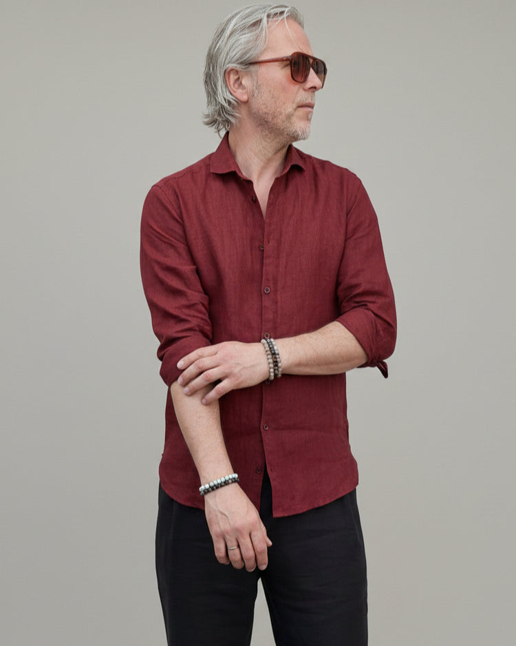 Man wearing a red shirt and sunglasses against a light grey backdrop