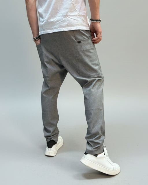 Person wearing grey dogtooth pants and white T-shirt and white sneakers on a gray floor.