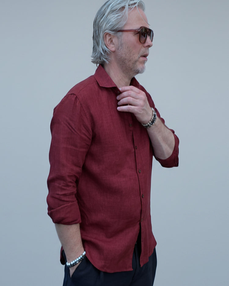 Man wearing a red shirt and sunglasses against a light grey backdrop
