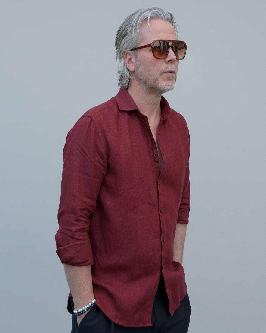 Man wearing a red shirt and sunglasses against a light grey backdrop
