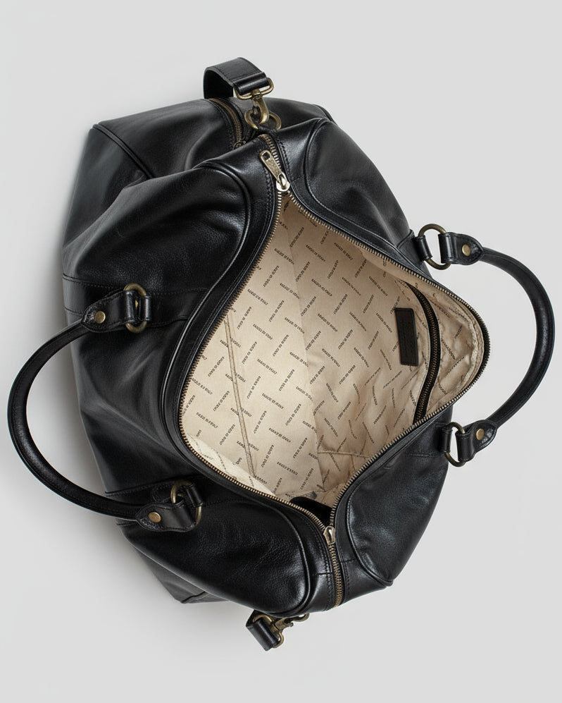 Black leather duffel bag with shoulder strap on a light gray background