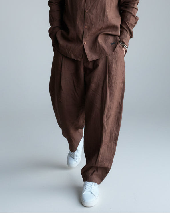 Man in a brown outfit standing against light grey backdrop