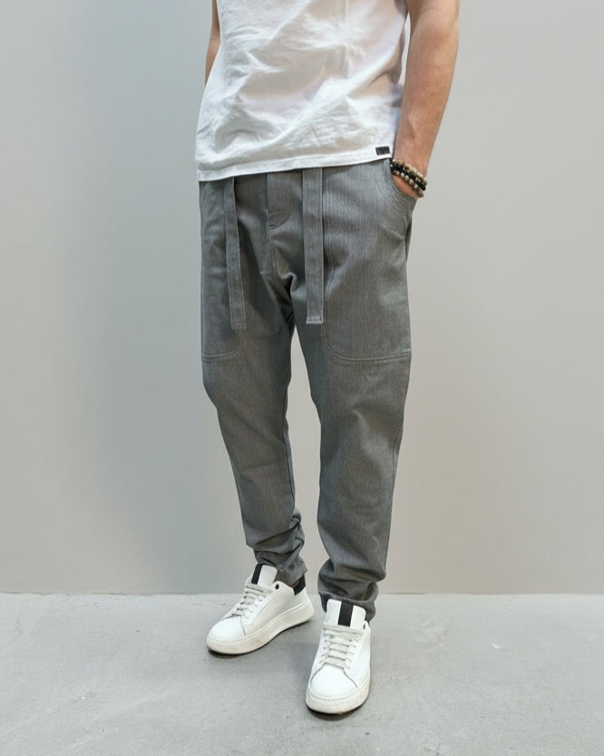 Person wearing grey dogtooth pants and white T-shirt and white sneakers on a gray floor.