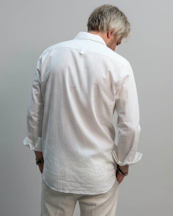 Model  wearing a white shirt and white pants in front of light grey backdrop