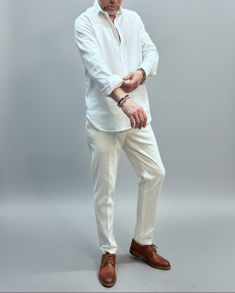 Model  wearing a white shirt and white pants in front of light grey backdrop