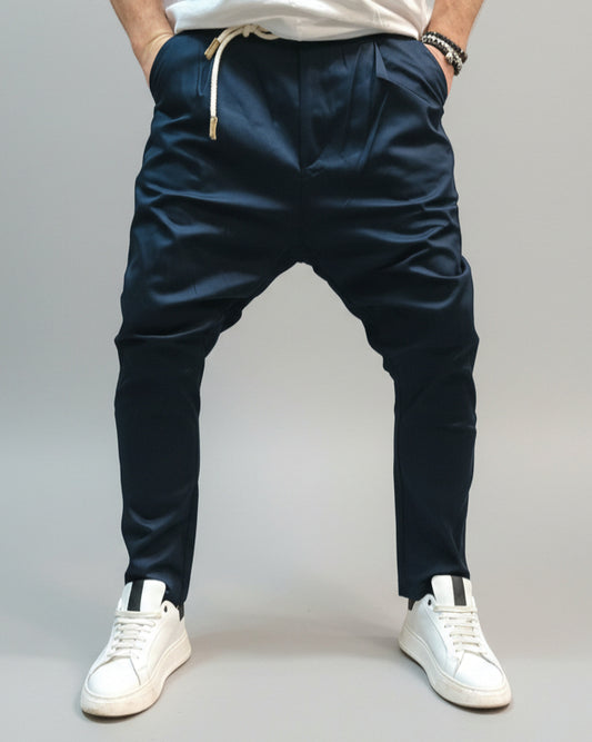 Model wearing navy blue pants in front of L. grey backdrop.
