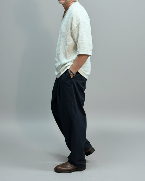 Person wearing a light-OFF-WHITE top and dark pants on a LIGHT GREY fabric backdrop.