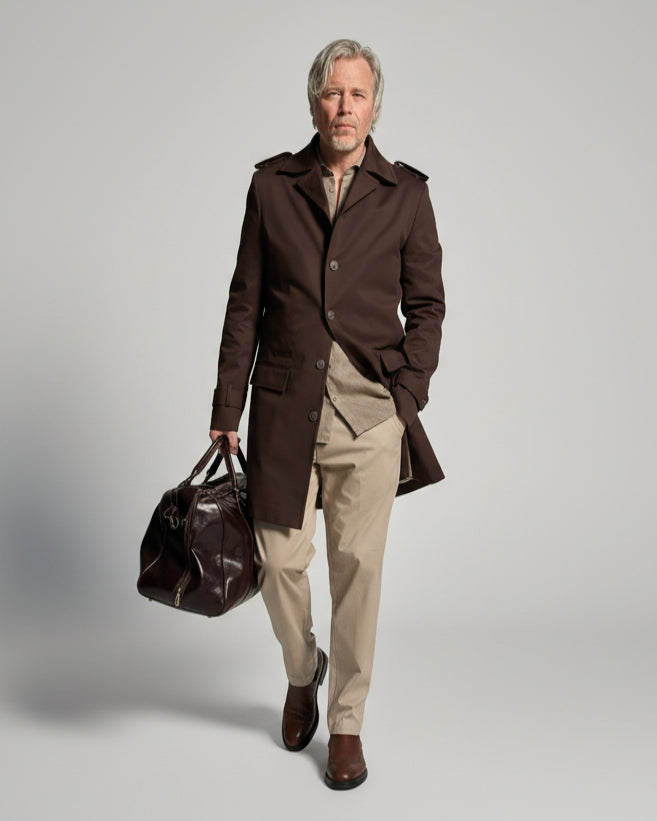 MODEL STANDING IN FRONT OF L. GREY BACKDROP WEARING A BROWN TRENCH COAT