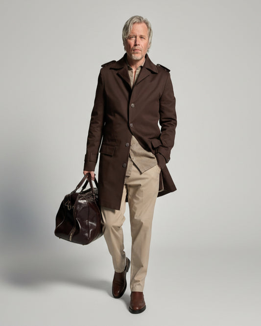 MODEL STANDING IN FRONT OF L. GREY BACKDROP WEARING A BROWN TRENCH COAT