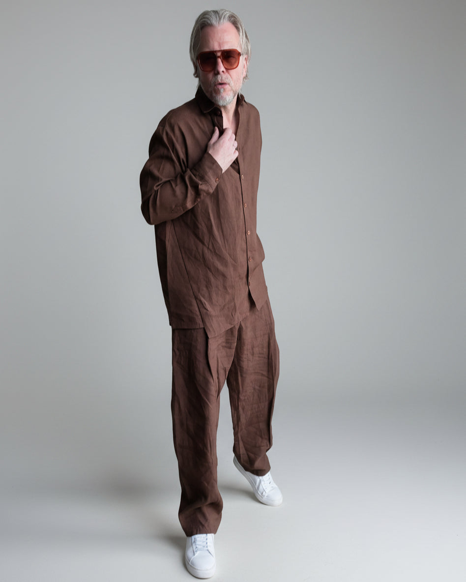 Man in a brown outfit standing against light grey backdrop