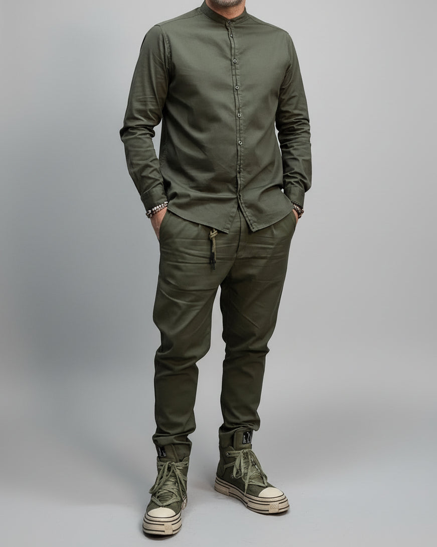 Person wearing a green military-style outfit with boots against a dark background in a dynamic position.