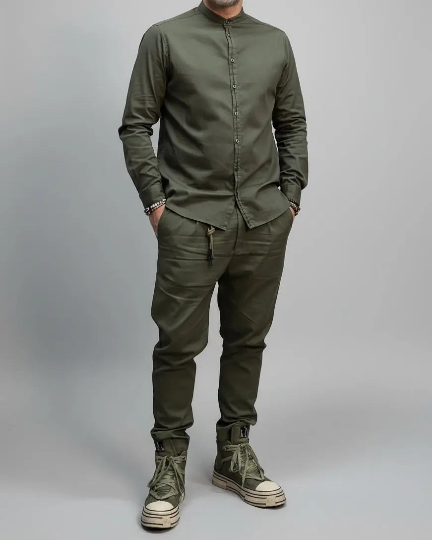 Person wearing a green military-style outfit with boots against a dark background in a dynamic position.