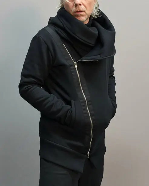 Person wearing a black outfit standing on a light grey surface with a blurred background.