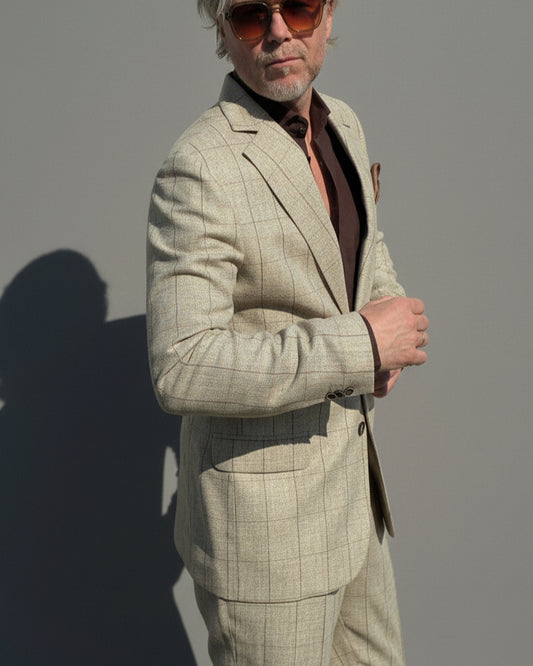 Model in a beige checked suit standing against a light grey backdrop