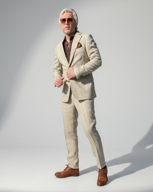 Person in a beige CHECKED suit standing in front OF LIGHT GREY BACKDROP