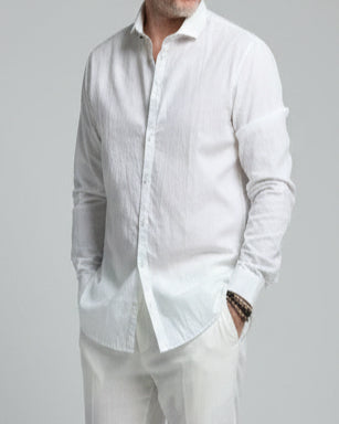 Model  wearing a white shirt and white pants in front of light grey backdrop