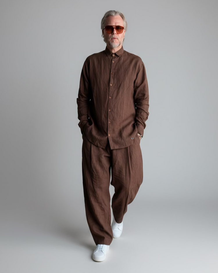 Man in a brown outfit standing against light grey backdrop