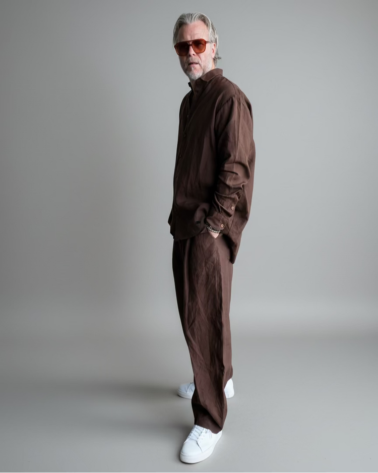Man in a brown outfit standing against light grey backdrop