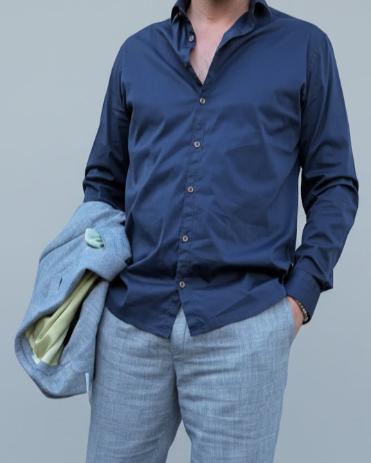 Person wearing a navy blue button-up shirt in front of light grey backdop