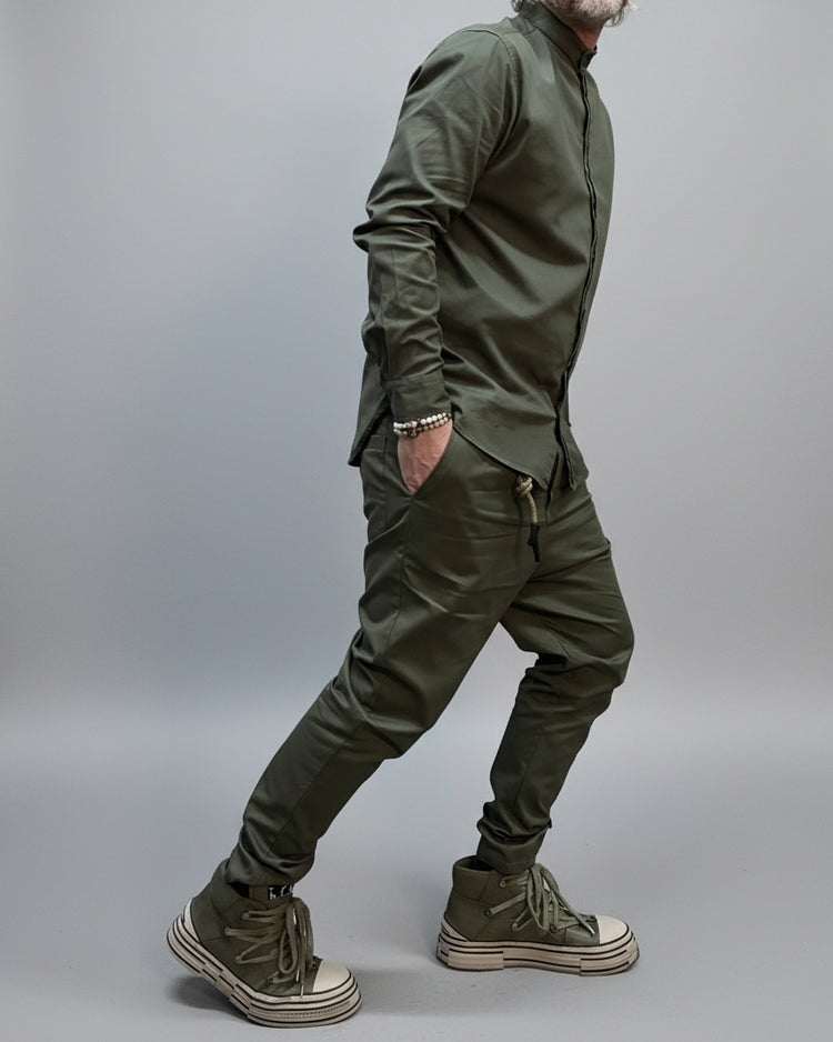 Man in green korean shirt and pants standing in a room with a black metal structure and gray floor in a dynamic position, and needs to be that!