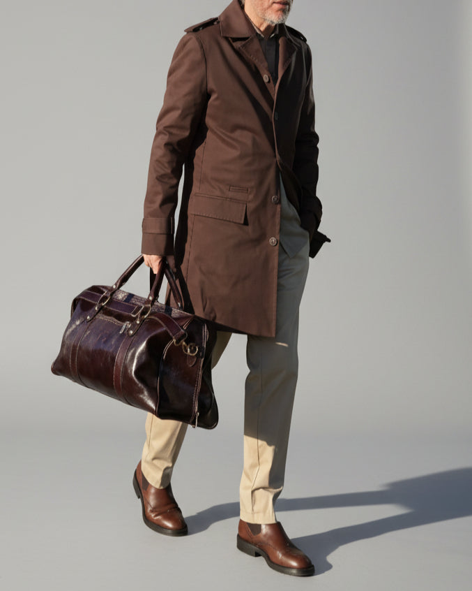 MODEL STANDING IN FRONT OF L. GREY BACKDROP WEARING A BROWN TRENCH COAT