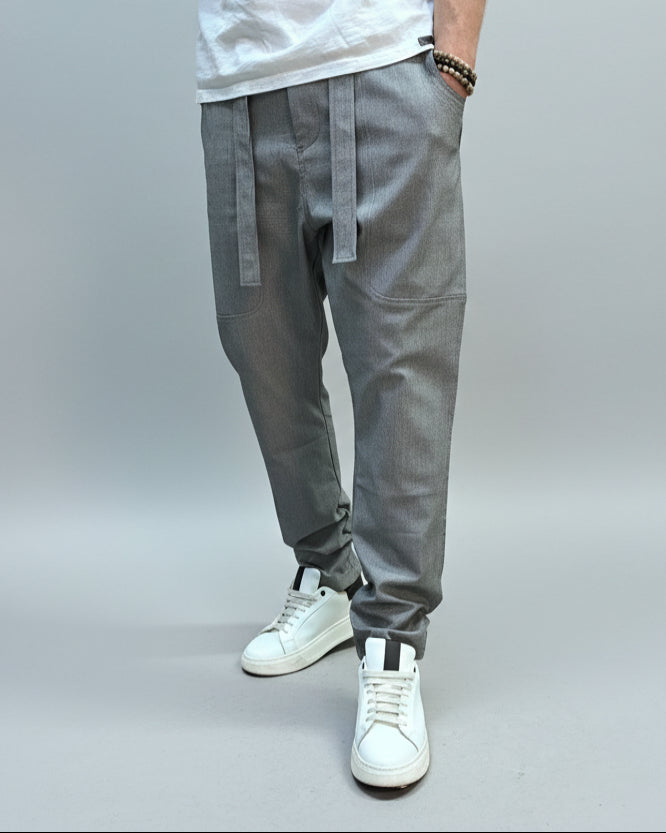Person wearing grey dogtooth pants and white T-shirt and white sneakers on a gray floor.