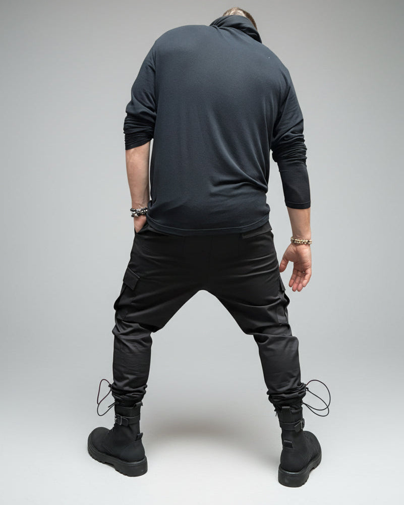 Person wearing black outfit and boots on a light gray floor. In a dynamic position