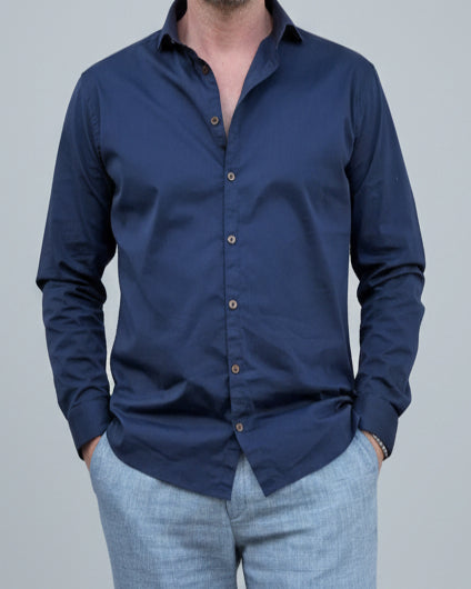 Person wearing a navy blue button-up shirt in front of light grey backdop