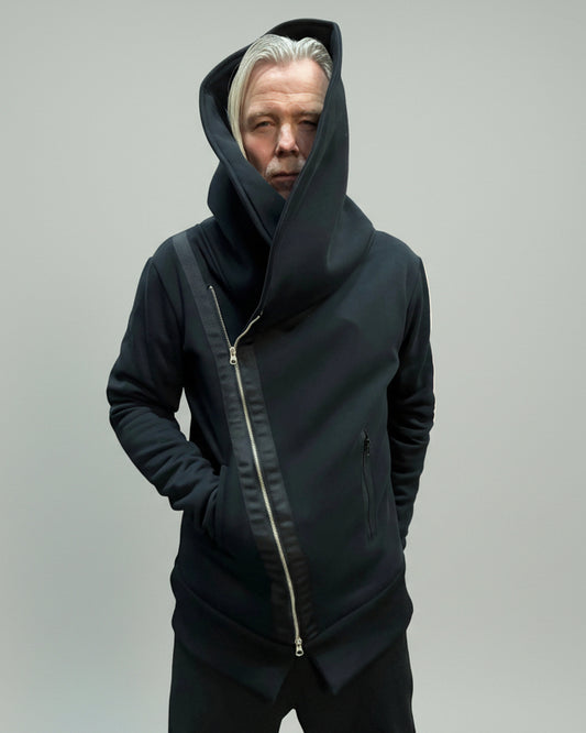 Model wearing a jumper in front of grey backdrop. one hand in backpocket and one in front pocket.