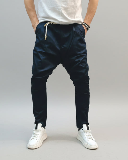Model wearing navy blue pants in front of L. grey backdrop.