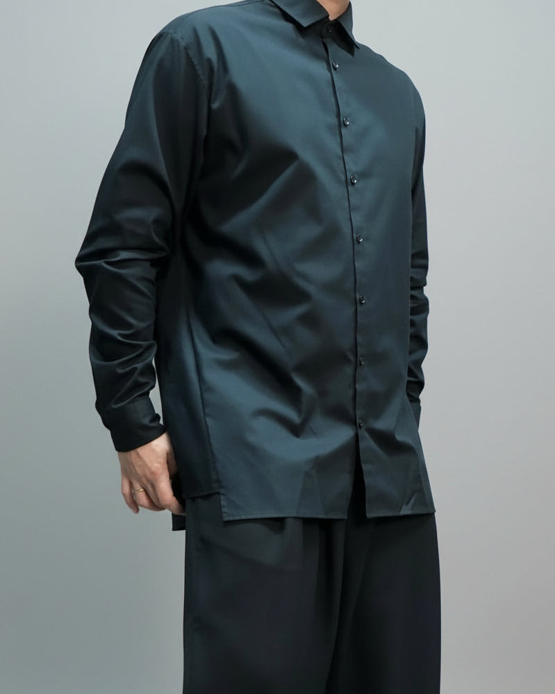 Person wearing a black oversized  shirt and pants against a plain background in a dynamic pose