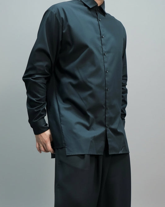 Person wearing a black oversized  shirt and pants against a plain background in a dynamic pose