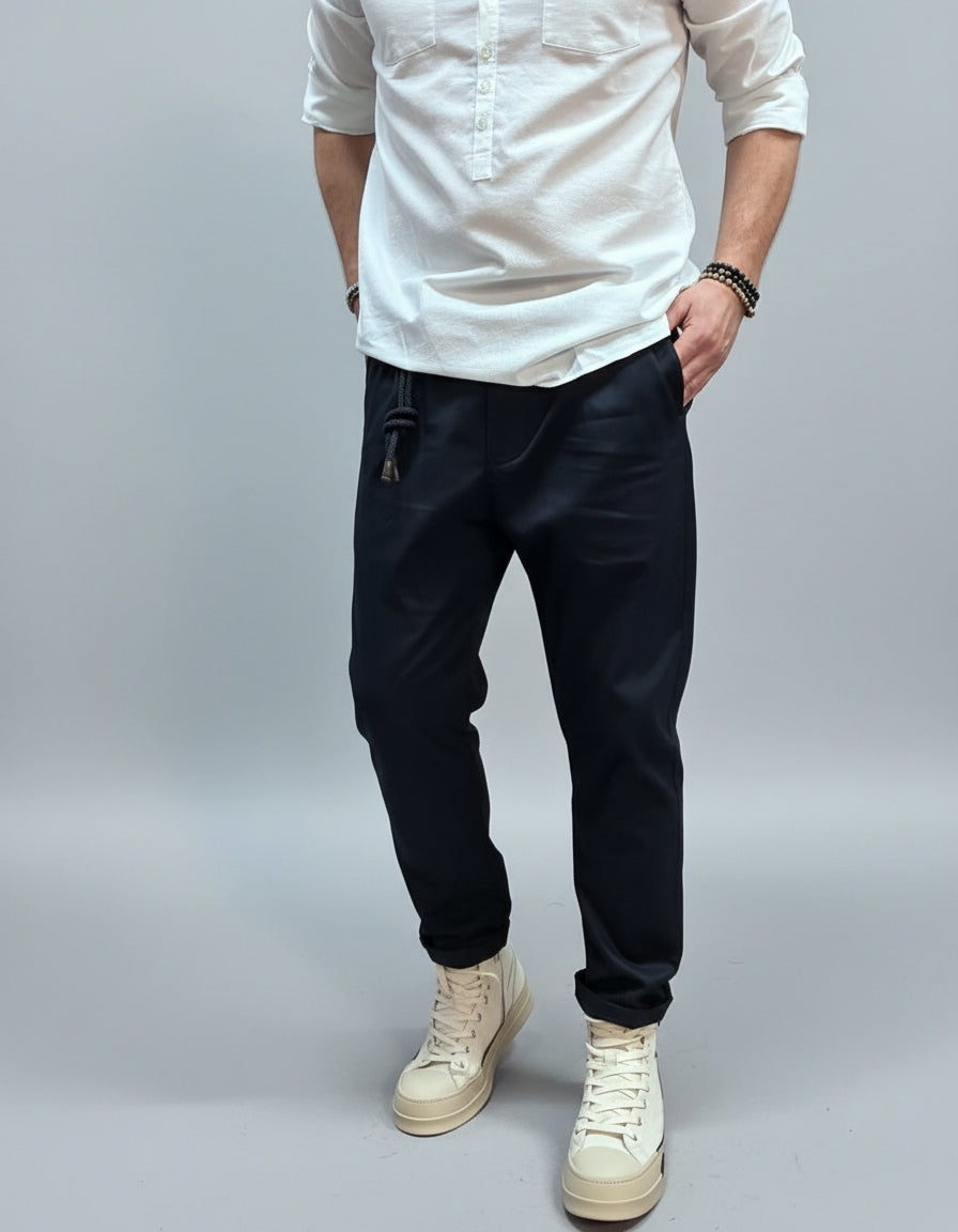 Person wearing a white shirt, navy blue pants, and white sneakers in an urban setting.