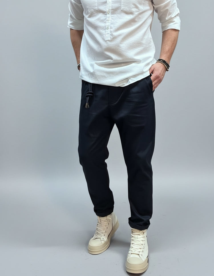 Person wearing a white shirt, navy blue pants, and white sneakers in an urban setting.