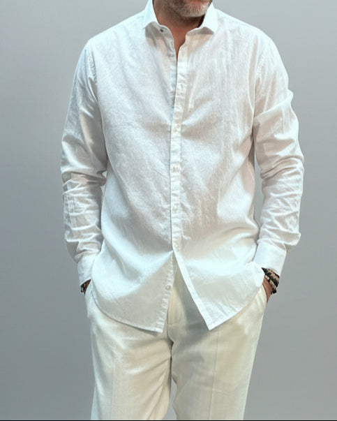 Model  wearing a white shirt and white pants in front of light grey backdrop