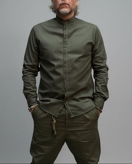 Person wearing a green korean shirt and pants in a room with dark walls and a concrete floor.