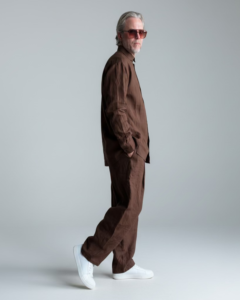 Man in a brown outfit standing against light grey backdrop