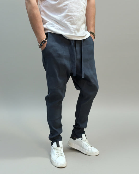 Person wearing a white shirt and blue pants standing on a gray floor with a brown fabric draped over them.