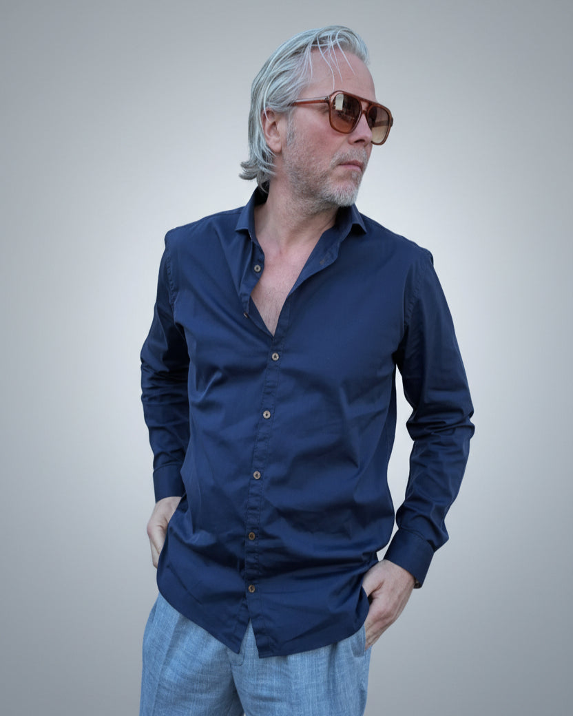Person wearing a navy blue button-up shirt in front of light grey backdop