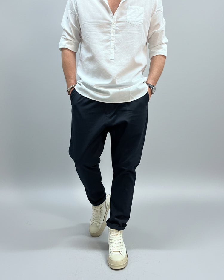 Person wearing a white shirt, navy blue pants, and white sneakers in an industrial setting.