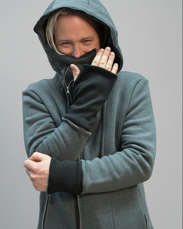 Person wearing a gray hoodie with a black zipper on a light grey background