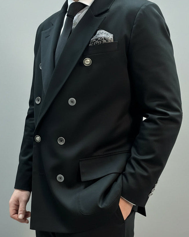 Black suit with a pocket square on a neutral background model in dynamic position.
