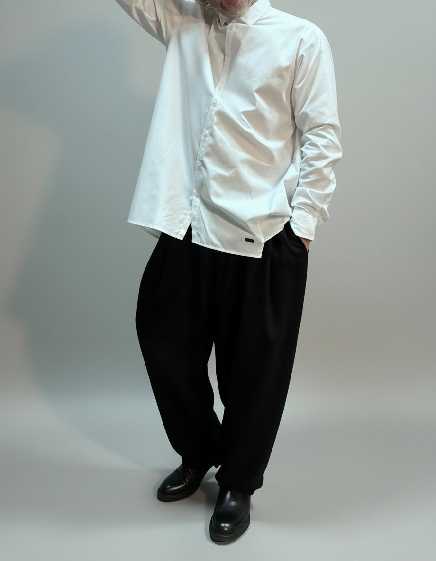 Person wearing a oversized white shirt and black pants in a dynamic pose