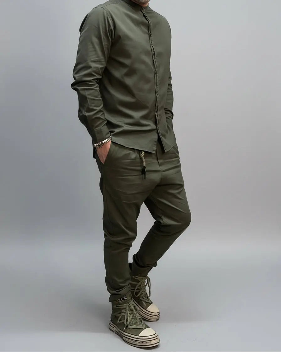 Person wearing a green outfit with matching shoes against a black metal door background