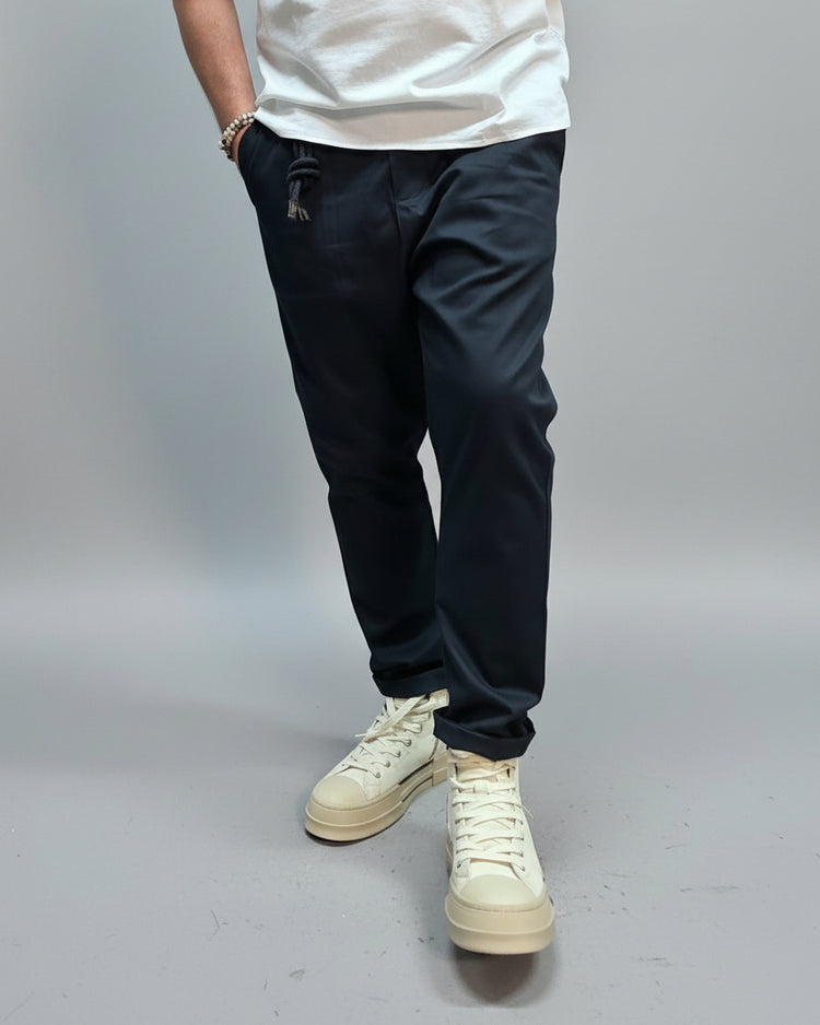 Person wearing navy blue pants and white sneakers in an industrial setting
