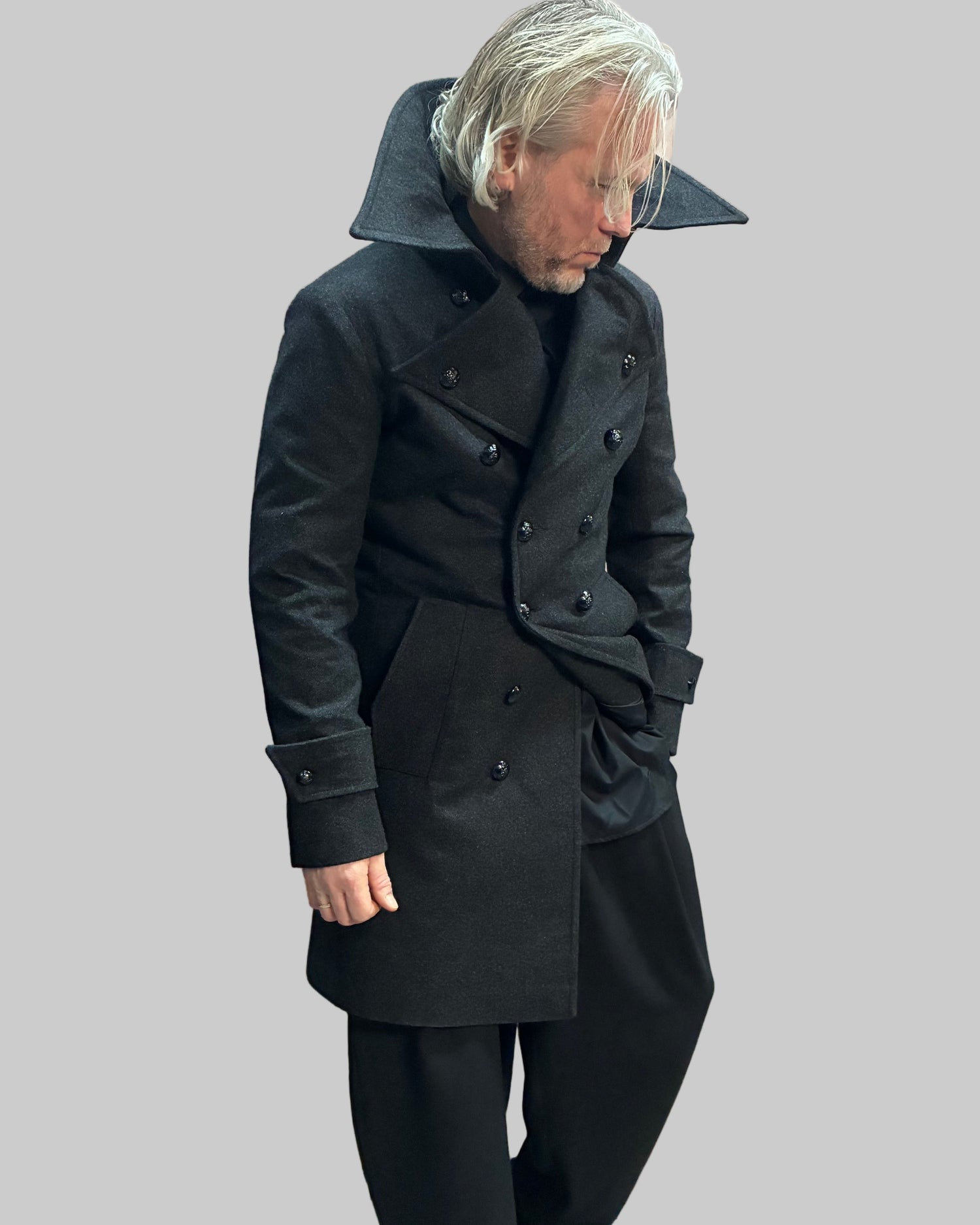 Person wearing a long grey coat in a dynamic position.